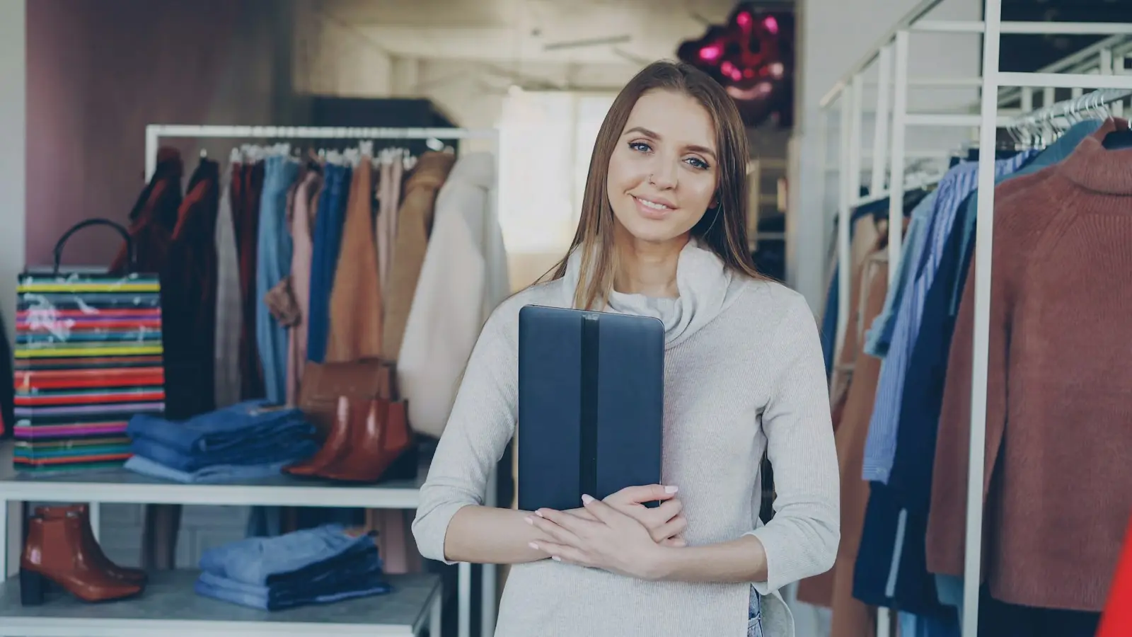 Lojista sorrindo em frente às araras de roupa